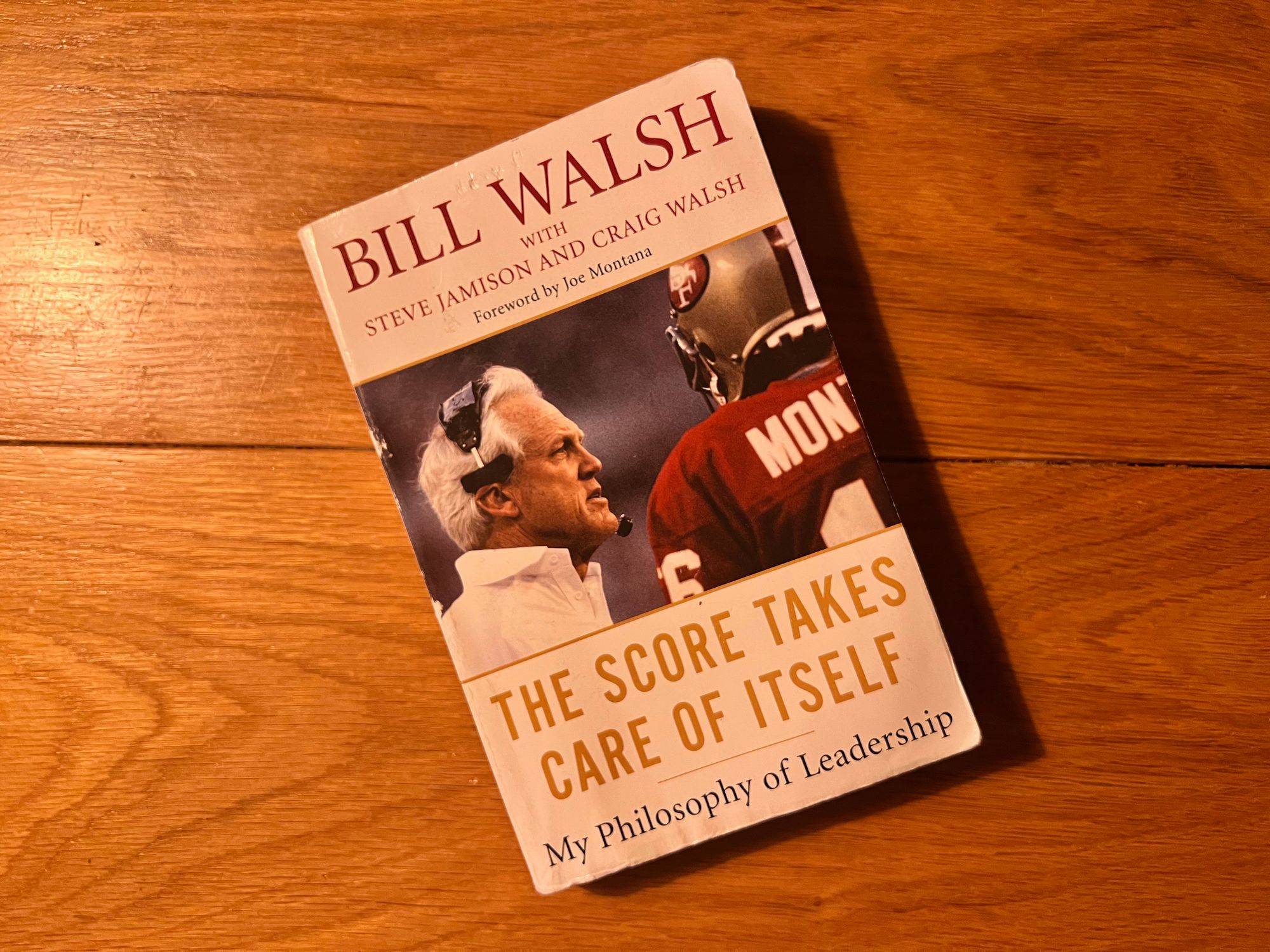 The book "The Score Takes Care of Itself" with a wood background.